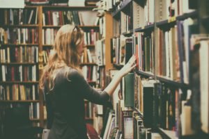 Eine Frau steht an einem Bücherregal in einer Buchhandlung.