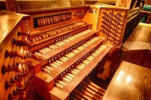 Tastatur einer alten Orgel mit Bank, Tasten und Registern.