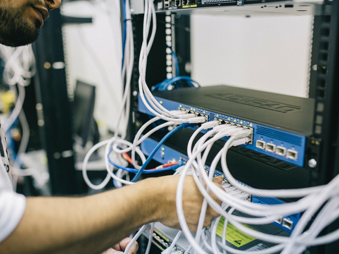 Ein Mann befestigt Netzwerkkabel an einer Servereinheit.