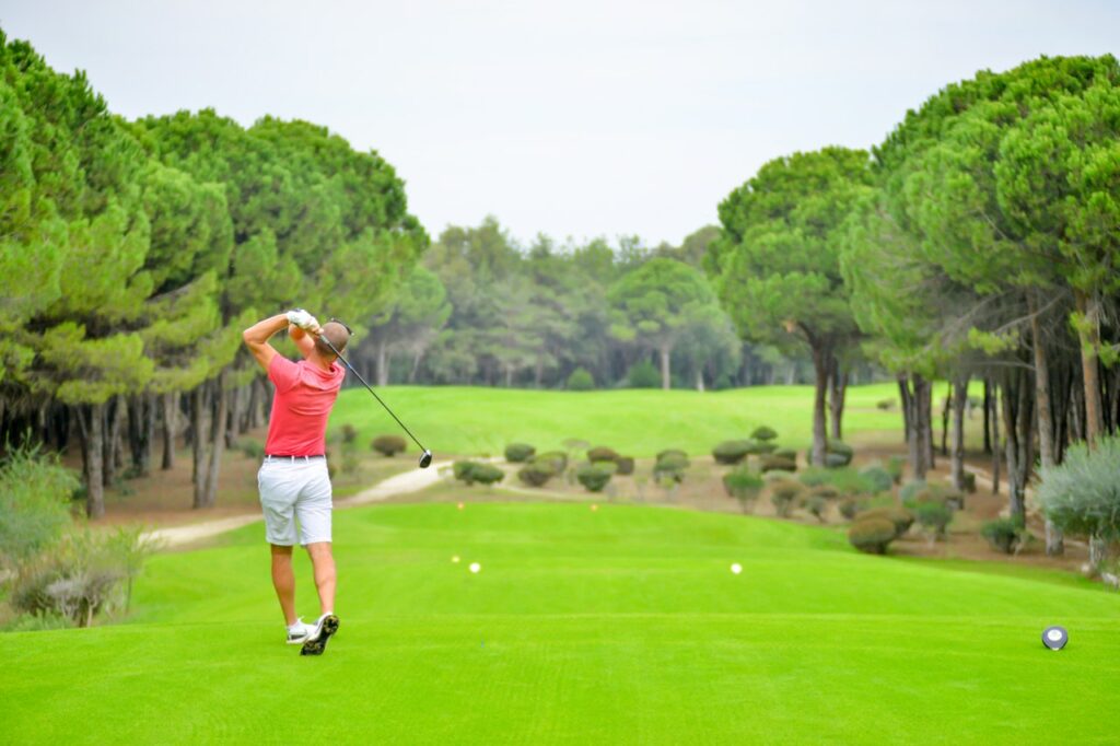 Golfspieler am Abschlag eines sattgrünen Golfplatzes.