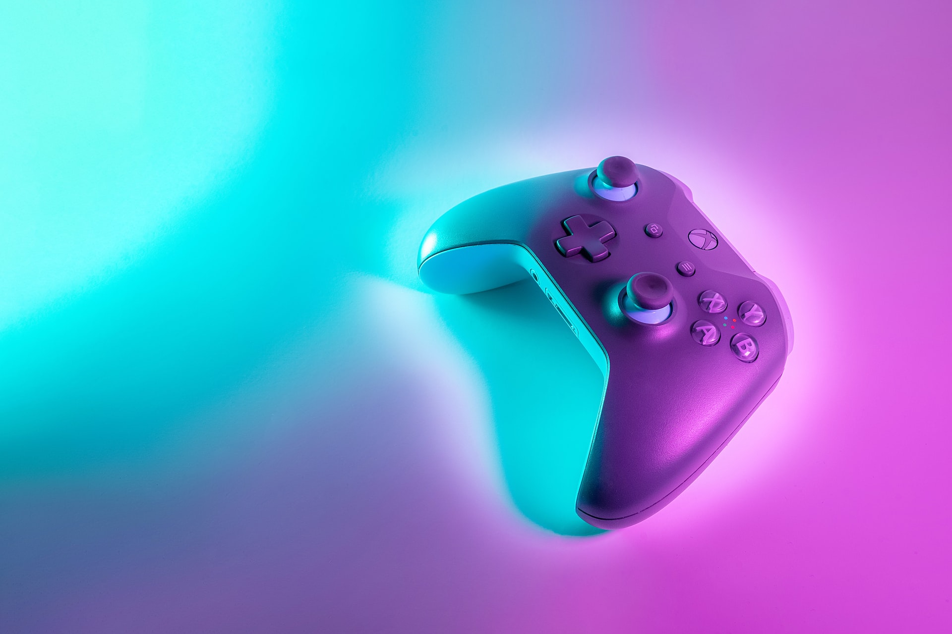Ein Xbox-Controller liegt auf türkis-pinker beleuchteten Oberfläche.