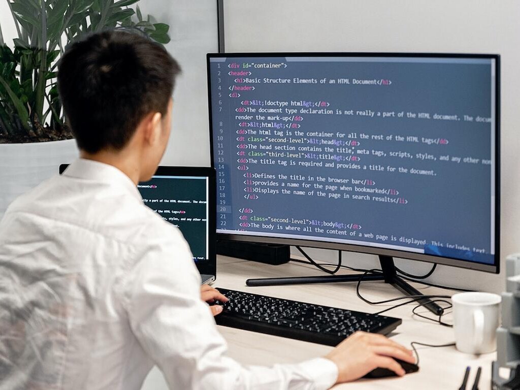 Ein Mann vor einem Computerbildschirm mit Programmiersprache.