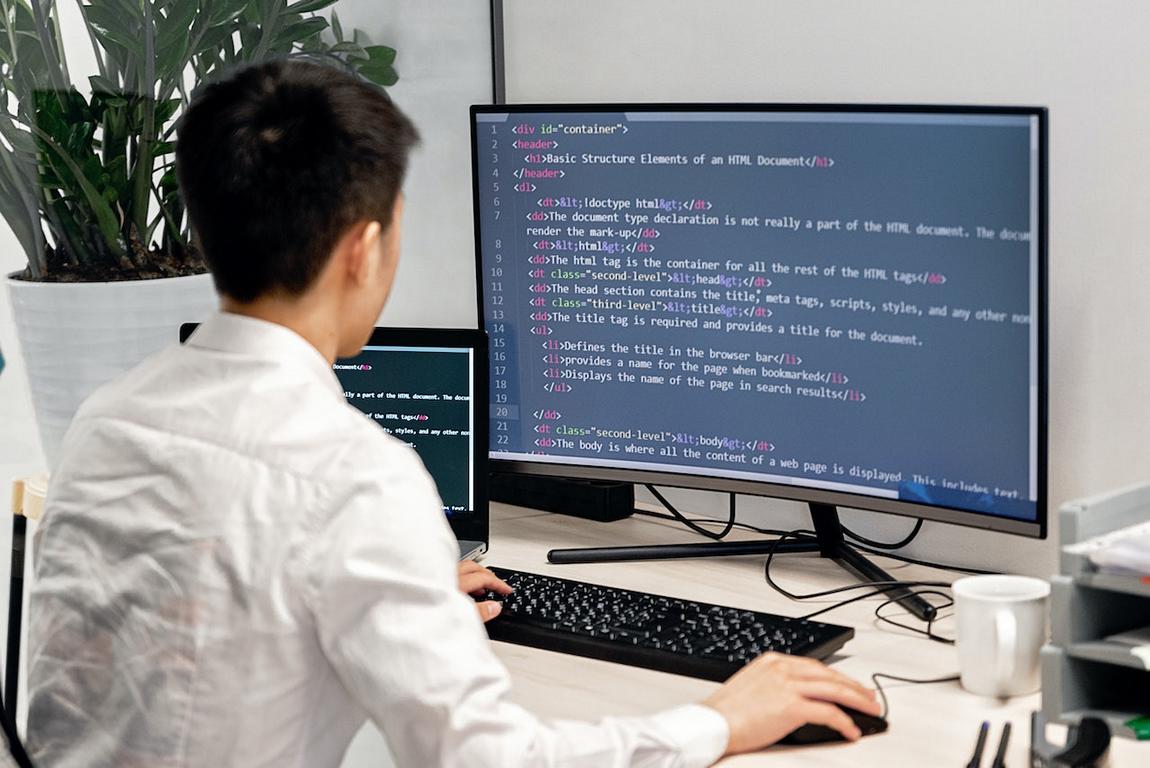 Ein Mann vor einem Computerbildschirm mit Programmiersprache.