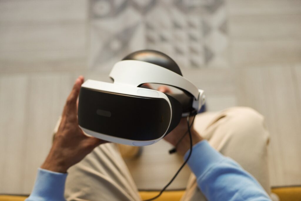 Eine sitzende Person hält eine VR-Brille in der Hand.