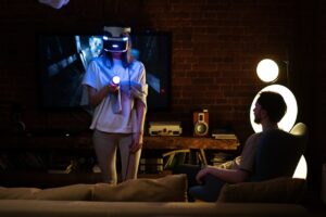 Zwei Personen im Wohnzimmer beim Spielen eines Computerspiels mit VR-Brille.