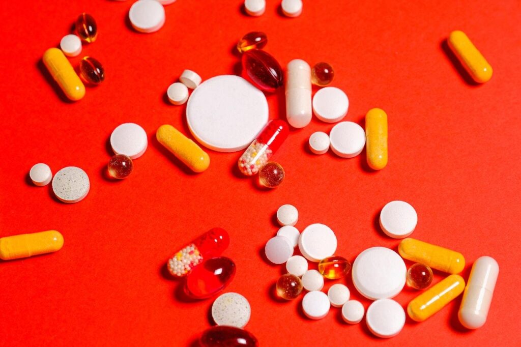 Auf einer roten Fläche liegen Tabletten und Pillen in unterschiedlichen Größen und Farben.