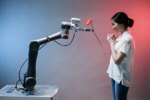 Ein Roboterarm überreicht einer jungen Frau eine rote Blume.