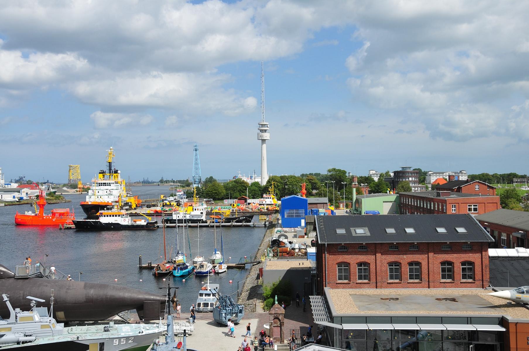 Hafen in Wilhelmshaven mit Gebäuden, Schiffen und Fernsehturm.