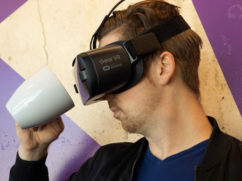 Mann mit VR-Brille schaut in eine Kaffeetasse.