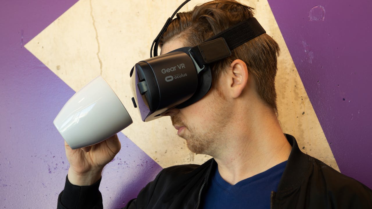 Mann mit VR-Brille schaut in eine Kaffeetasse.
