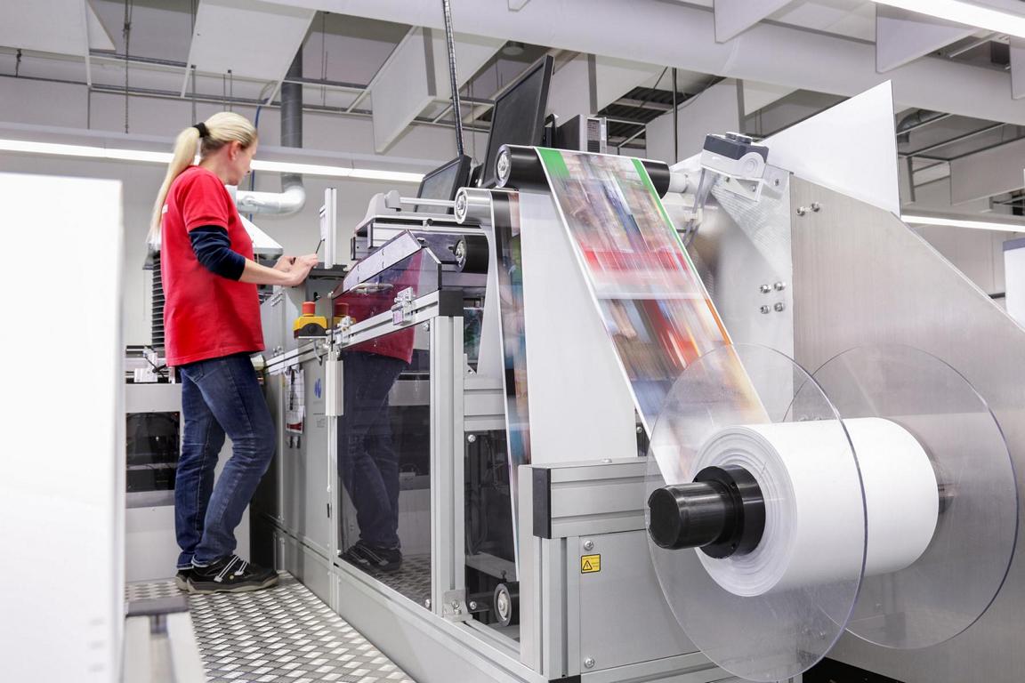 Eine Frau steht an einer Maschine zur Herstellung von Foto-Druckerzeugnissen.