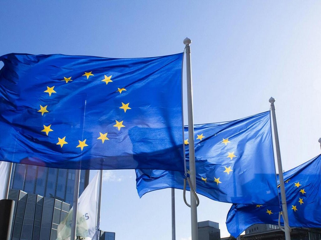 Drei wehende Europaflaggen nebeneinander vor einem Gebäude.